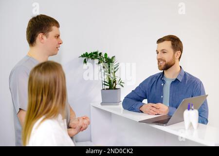 Patient reconnaissant. Homme debout à la réception de la clinique dentaire et très heureux pour le traitement Banque D'Images