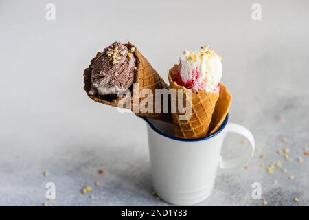 Tasse blanche avec des cornets alvéolés de crème glacée sur une table en béton Banque D'Images