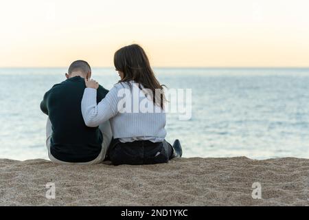 Une femme consolant son amie en étant assise sur le sable à la plage Banque D'Images