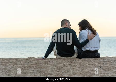 Homme consolant son ami tout en étant assis sur le sable à la plage Banque D'Images