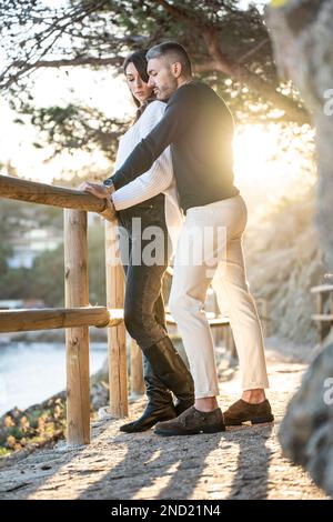 Un couple amoureux dans un sentier près de la plage avec le coucher de soleil sur le fond Banque D'Images