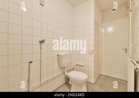 Décoration intérieure de la salle de bains avec murs carrelés blancs et cuvette de toilettes placé près de la porte Banque D'Images