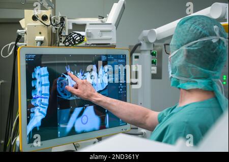 15 février 2023, Saxe-Anhalt, Halle (Saale): Le médecin principal Bernhard Ullrich vérifie le canal à vis à l'écran lors d'une simulation de chirurgie rachidienne lors d'un événement de presse. L'hôpital Bergmannstrost de Halle met en service un nouveau système d'exploitation robotique. Il est équipé d'un bras robotique, d'un robot d'imagerie 3D et d'un système de navigation numérique. Photo: Heiko Rebsch/dpa Banque D'Images