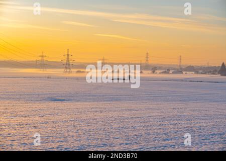 Lignes électriques au-dessus de champs couverts de neige au coucher du soleil près d'Ifield, Gravesend Kent Banque D'Images