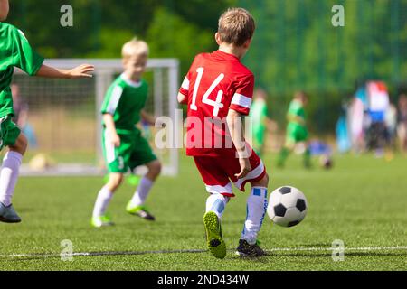 Les enfants de l'école dans un match de football. Match de football pour les écoliers. Un jeune joueur de football se dirige vers le but. Les enfants participent à un match de football Banque D'Images