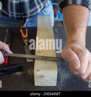 Image des mains d'un artisan charpentier qui lisse un morceau de bois avec une batte. Classement et nettoyage du bois. Banque D'Images