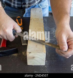 Image des mains d'un artisan charpentier qui lisse un morceau de bois avec une batte. Classement et nettoyage du bois. Banque D'Images