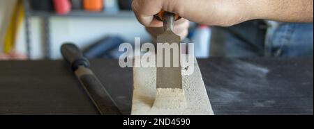 Image des mains d'un artisan manuel tenant un marteau et un burin de charpentier tout en faisant du travail et en sculptant du bois. Travail de bricolage en laboratoire. Banque D'Images