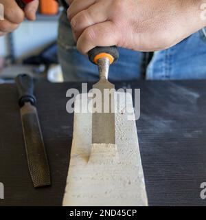 Image des mains d'un artisan manuel tenant un marteau et un burin de charpentier tout en faisant du travail et en sculptant du bois. Travail de bricolage en laboratoire. Banque D'Images