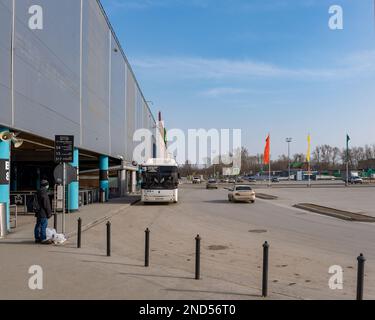 Novosibirsk, Russie-12 avril 2020. Un homme seul dans un masque médical se tient avec des sacs d'épicerie à l'arrêt d'hypermarché Auchan attendant un bus à cause de la Banque D'Images