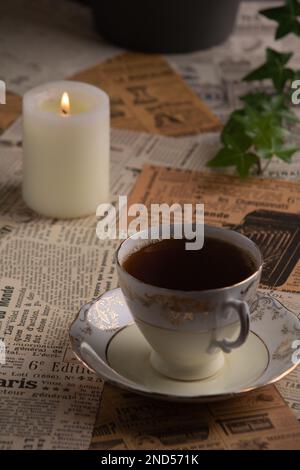 photo sur les vieux coupures de journaux il y a une tasse de café à côté d'une bougie allumée Banque D'Images