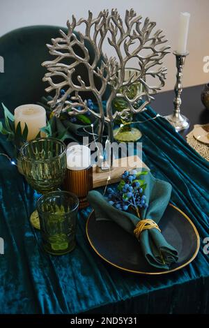 Table pour un mariage ou un autre dîner avec traiteur. La table de luxe servie à l'intérieur dans les couleurs vertes. Table en bois sombre, magnifique restaurant le soir Banque D'Images