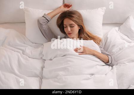 Femme sous une couverture blanche et chaude dormant dans le lit à l'intérieur, au-dessus de la vue Banque D'Images