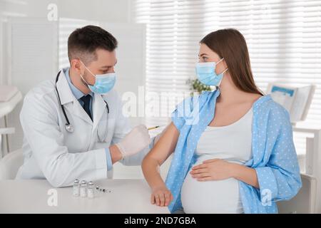 Médecin vaccinant la femme enceinte contre Covid-19 en clinique Banque D'Images