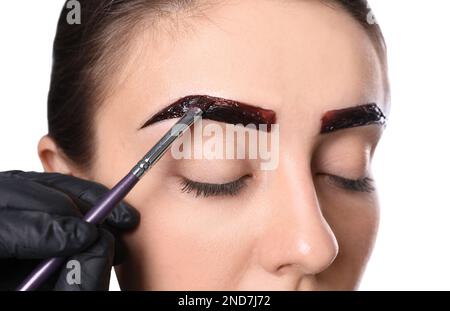 Esthéticienne appliquant la teinte pendant la procédure de correction des sourcils sur fond blanc, gros plan Banque D'Images