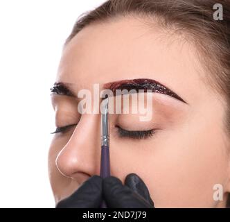 Esthéticienne appliquant la teinte pendant la procédure de correction des sourcils sur fond blanc, gros plan Banque D'Images