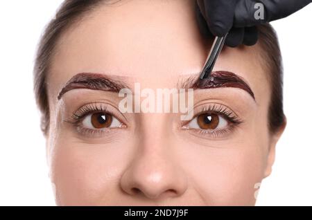 Esthéticienne appliquant la teinte pendant la procédure de correction des sourcils sur fond blanc, gros plan Banque D'Images