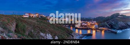 Vue sur la petite ville de Viavelez avec des reflets de lanternes dans le port sur la côte de l'Espagne et où la lune se brise à travers le nuage de coucher de soleil Banque D'Images