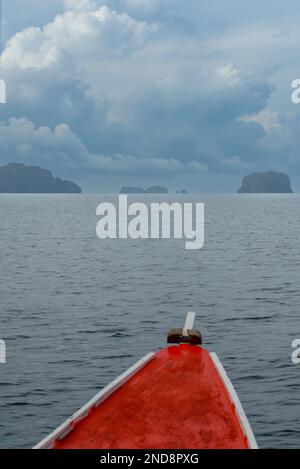 Cette photo capture l'essence des Philippines, avec un bateau traditionnel en bois qui navigue sur des eaux turquoise cristallines, entouré d'un vert luxuriant Banque D'Images