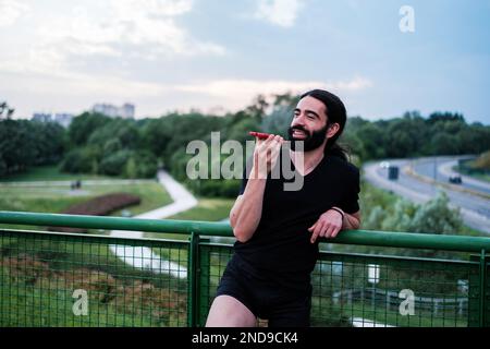 Jeune homme avec une jambe prothétique reposant de faire du sport à l'aide de son smartphone. Concept : surmonter, sports, technologie Banque D'Images