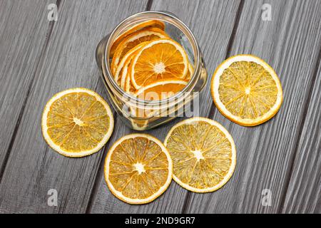 Séchez les tranches d'orange sur la table et dans un pot en verre. Pose à plat. Arrière-plan en bois sombre. Banque D'Images