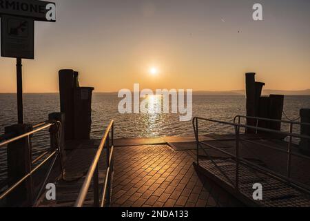 Magnifique coucher de soleil sur le magnifique lac de Garde en Italie, avec le soleil se reflétant sur l'eau calme et créant une atmosphère paisible. Parfait pour les Banque D'Images