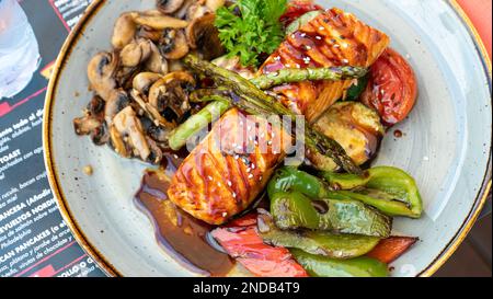 Vue rapprochée des oiseaux du saumon canadien fraîchement grillé à la sauce teriyaki servi avec des légumes grillés Banque D'Images