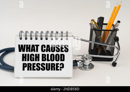 Concept médical. Sur la table sont des fournitures de bureau, un stéthoscope et un bloc-notes avec l'inscription - ce qui cause l'hypertension Banque D'Images