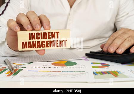 Concept d'entreprise. Sur la table se trouvent des diagrammes et des diagrammes d'affaires dans les mains d'un bloc de bois avec l'inscription - gestion des incidents Banque D'Images
