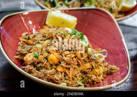 un savoureux bol de riz frit aux crevettes de style oriental servi avec un coin de citron Banque D'Images