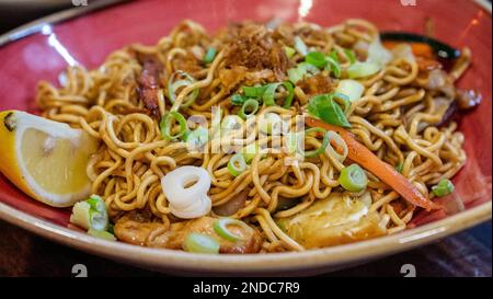 une image en gros plan des nouilles sautées fraîchement préparées de style oriental servies dans un bol rouge Banque D'Images