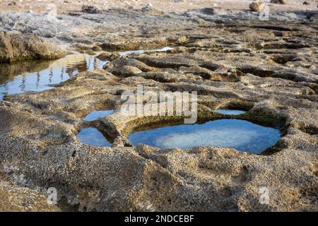 côte rocheuse avec des renfoncements ronds avec de l'eau, dans laquelle le ciel est réfléchi. Fond d'écran Banque D'Images