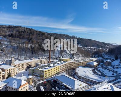 Vue aérienne d'un drone de l'ancienne usine avec une grande cheminée lors d'une journée d'hiver ensoleillée dans la ville de Tanvald, République tchèque Banque D'Images