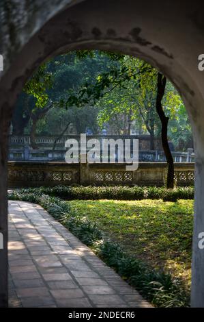 Passage voûté d'un bâtiment vieux menant au parc avec arbres et clôture Banque D'Images