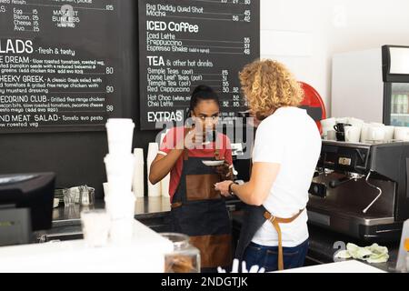Joyeux baristas hommes et femmes portant des tabliers et buvant du café dans le café. Café, temps libre et concept de ville. Banque D'Images