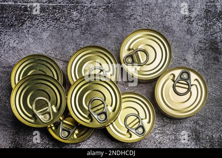 Jeu de petits boîtes de rangement circulaires en métal avec languettes faciles à ouvrir sur une surface grise Banque D'Images