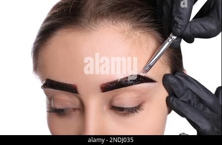 Esthéticienne appliquant la teinte pendant la procédure de correction des sourcils sur fond blanc, gros plan Banque D'Images