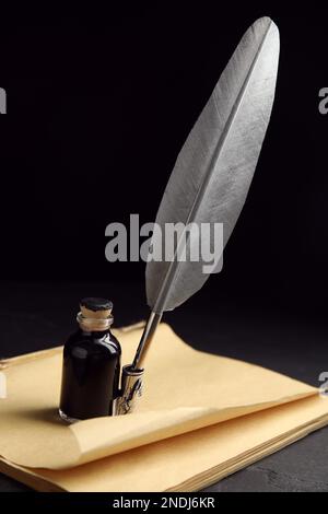 Stylo plume, bouteille d'encre et vieux papier sur table noire Banque D'Images