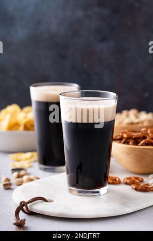 Bière brune en grands verres, bière et en-cas sur la table Banque D'Images