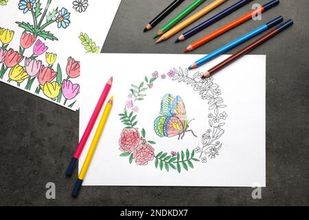 Pages de coloriage avec dessins d'enfants et jeu de crayons sur table grise, plat Banque D'Images