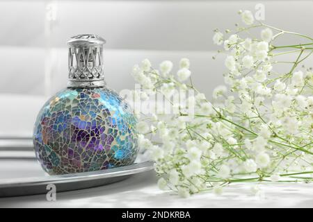 Belle lampe à purifier catalytique et fleurs sur le seuil de la fenêtre. Élément intérieur Banque D'Images