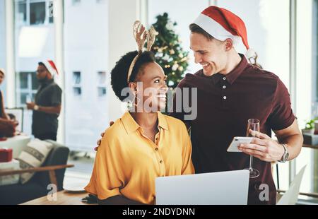 Im si heureux vos blogs faisant si bien miel. Un jeune couple joyeux souriant tout en utilisant un ordinateur portable ensemble le jour de Noël à la maison. Banque D'Images