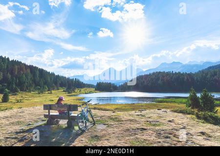Une fille se repose pendant une balade à vélo près d'un lac de montagne dans les alpes suisses Banque D'Images