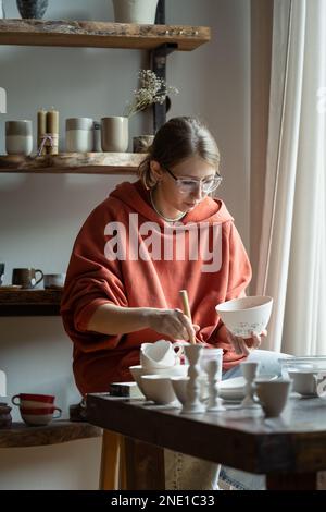 Focalisé artisan fille travaille sur la fabrication de produits en céramique d'argile dans le studio de potter pour la commande personnalisée Banque D'Images