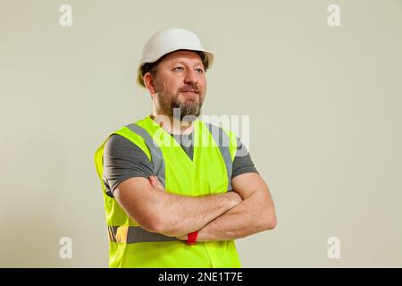 Un homme travailleur dans un gilet et un casque de construction blanc dans différentes poses se tient sur un fond blanc Banque D'Images