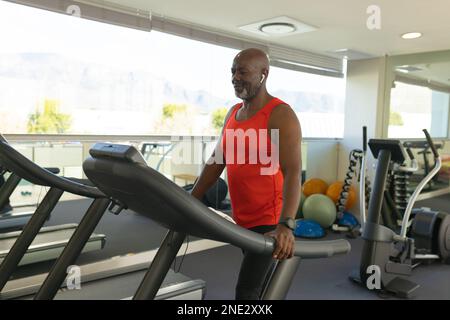 Homme senior afro-américain debout sur le tapis roulant à la maison. concept de vie et de vie senior retraite Banque D'Images