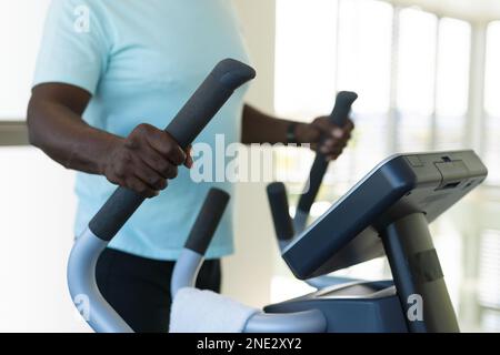 Section moyenne de l'africain américain senior homme utilisant machine elliptique à la salle de gym. concept de vie et de vie senior retraite Banque D'Images