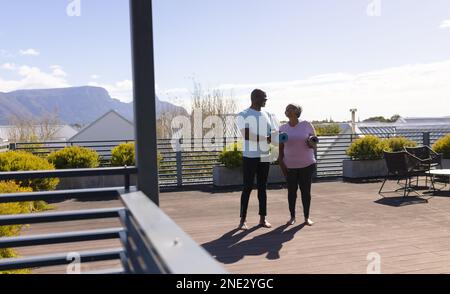 Couple senior afro-américain tenant des tapis de yoga debout sur la terrasse à la maison. concept de vie et de vie senior retraite Banque D'Images