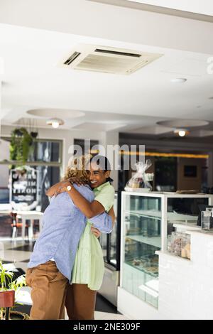 Joyeux couple divers embrassant et portant des vêtements décontractés dans le café. Café, temps libre et concept de ville. Banque D'Images