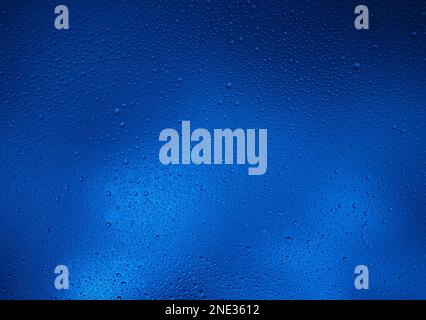 Fond bleu foncé brillant avec gouttes d'eau contrastées. Banque D'Images